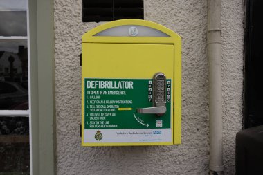 Yellow defibrillator box on a wall in Knaresborough Yorkshire, UK