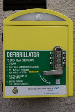 Closeup of yellow defibrillator box on a wall in Knaresborough Yorkshire, UK