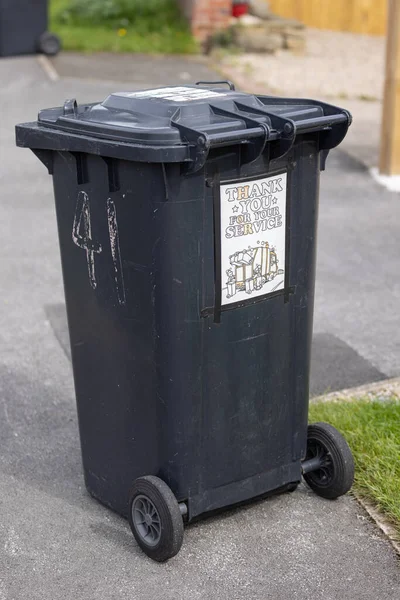 Plastic garbage wheelie bin on the street with a sticker in support of NHS with the words Thank you for your service in Harrogate, Yorkshire UK