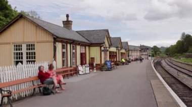 Couple sitting on bench at Embsay and Bolton Abbey Steam Railway station platform in Yorkshire