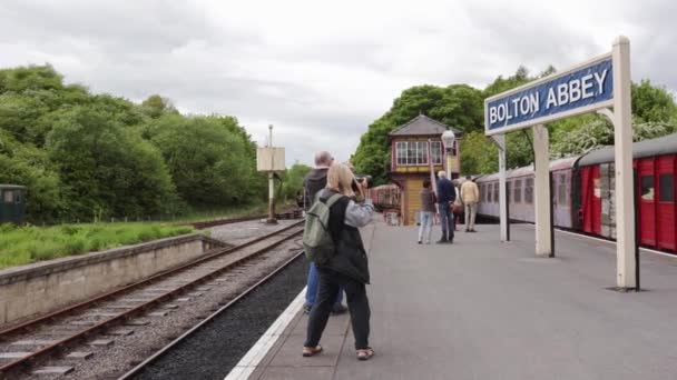 Photographers Taking Photos Bolton Abbey Sign Platform Train Station Yorkshire — Vídeo de Stock