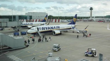 İnsanlar arka planda hava trafik kontrol kulesiyle Londra Stansted havaalanı pistinde Ryanair uçağını indiriyor.