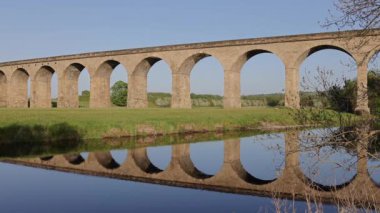 Beautiful reflection in the water of Arthington viaduct near Otley with train crossing the bridge a blue clear day