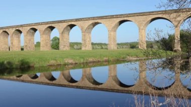 Reflection of Arthington viaduct near Otley in the water on a blue clear day