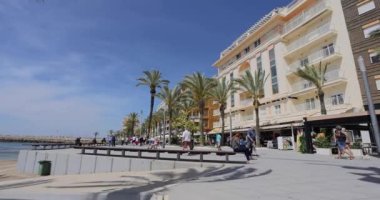 People walking and sitting on a bench at a popular tourist promenade in Torrevieja at Costa Blanca in Spain