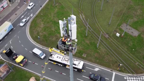 技術者はアントワープ市内の電気通信アンテナタワーで働いています 上から見たドローンの空中風景 — ストック動画
