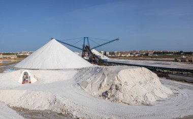 Torrevieja tuz madeninde fotoğraf çeken turistler, arkada makine ve tuz tepesi bulunuyor.