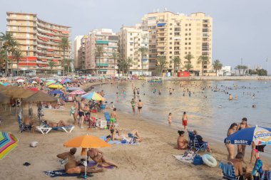  Tatilciler, arka planda dairelerle İspanya 'nın Torrevieja sahilinin keyfini çıkarıyorlar.