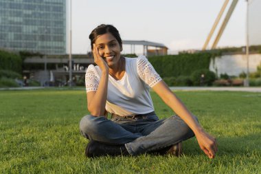 Güzel gülümseyen Hintli bir kadının otantik portresi. Parktaki cama bakarak güneşli günlerin tadını çıkarıyor. 