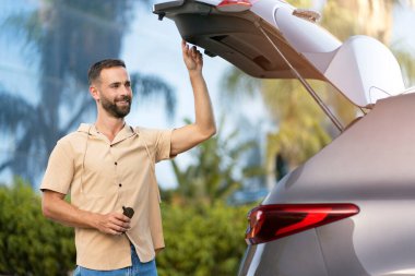 Gülümseyen Latin şoför arabanın bagajını açıyor. Ulaşım kavramı