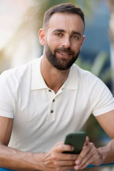 Portrét Pohledného Usměvavého Latinskoamerického Muže Držícího Mobilní Telefon Jak Dívá — Stock fotografie
