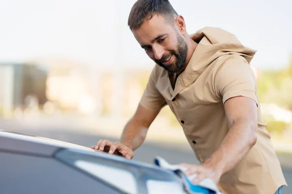 Knappe Lachende Man Met Een Baard Die Zijn Auto Schoonmaakt — Stockfoto