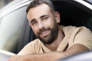 Yeni rahat bir arabada oturmuş kameraya bakarken gülümseyen sakallı adamın portresini yakından çek. Ulaşım kavramı 