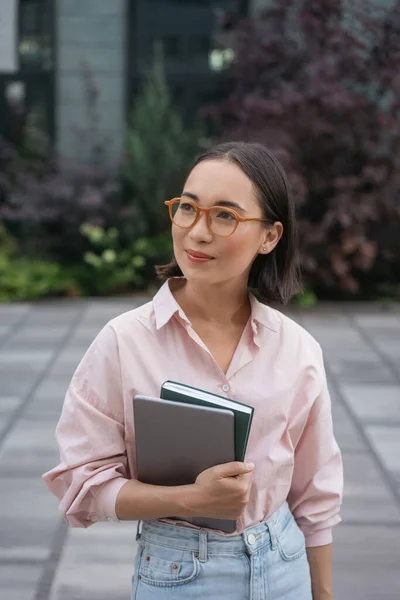 スタイリッシュなメガネ保持本を身に着けている普及したアジアの学生 大学のキャンパス内のラップトップスタンド 教育理念 — ストック写真