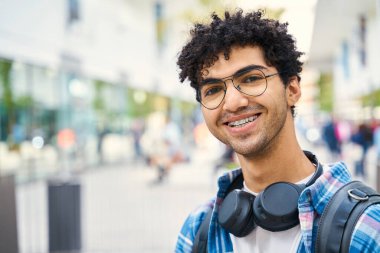 Kameraya bakan, kulaklık takan, gülümseyen, çekici bir adamın portresi.