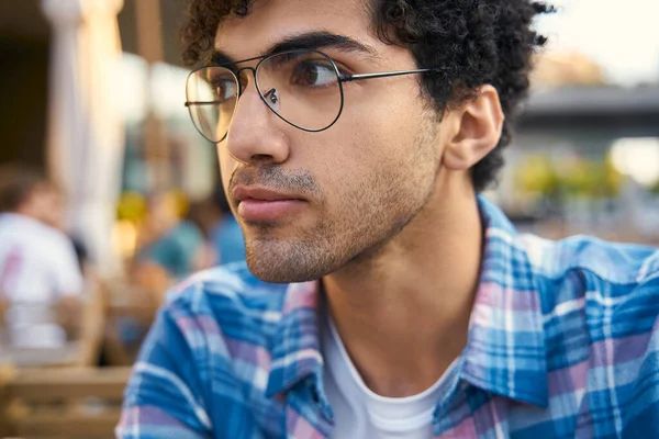 眼鏡を身に着けているハンサムな中東人男性が通りに座っている — ストック写真