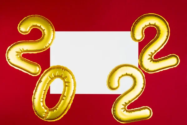 Ano Novo 2022. Números dourados com lista de papel branco em vermelho com espaço de cópia — Fotografia de Stock