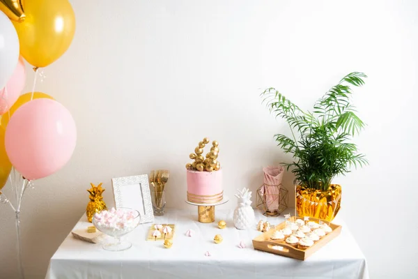 Tavolo festivo con torta e palloncini. Decorazione rosa e oro Foto Stock