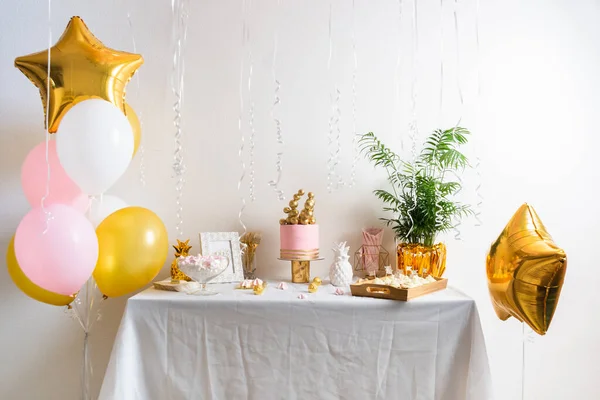 Tavolo festivo con torta e palloncini. Decorazione rosa e oro Foto Stock