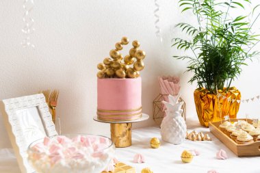 Pasta ve balonlarla dolu bir doğum günü masası. Pembe ve altın madalya.
