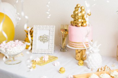 Pasta ve balonlarla dolu bir doğum günü masası. Pembe ve altın madalya.