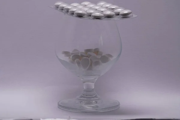 glass filled with pills covered with pills
