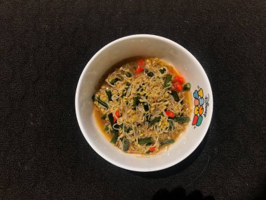 Siyah arka planı olan beyaz bir kabın içinde fasulye filizleniyor.