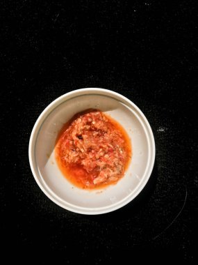 Koyu arkaplanda beyaz bir kabın içindeki acı biber sosu