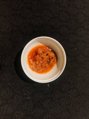 Koyu arkaplanda beyaz bir kabın içindeki acı biber sosu