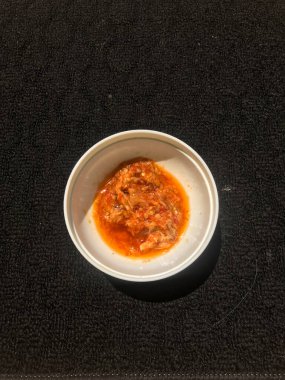 Koyu arkaplanda beyaz bir kabın içindeki acı biber sosu