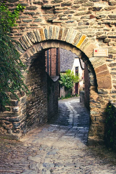 Ancient stone arched gate leading into Conques, France, along the pilgrimage road to the Camino de Santiago.