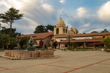 Çeşme ve avlu, mavi gökyüzü ve kabarık beyaz bulutlarla, The Carmel Misyon Bazilikası, San Carlos Borromeo 'nun misyonu, 1770 yılında Junipero Serra, Carmel-by-the-Sea, California USA