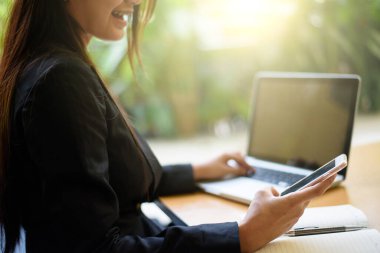 Dizüstü bilgisayarda çalışan ve yazı yazan bir kadının kesilmiş görüntüsü.