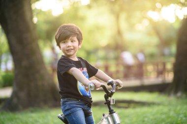 Bangkok Thailand - Oct 09, 2016 : happy cheerful child boy riding a bike in Park in the nature
