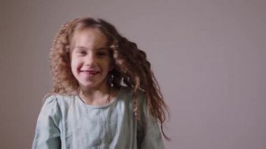 Komik küçük kız oturma odasında dans ediyor ve eğlenceli ve mutlu görünüyor. Mutluluk kavramı 