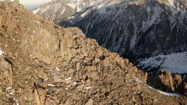 Kışın kayalık bir dağ manzarasında koşan bir adamın hava çekimi