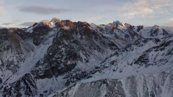 Vuelo aéreo sobre el paisaje montañoso de nieve cerca de la ciudad de Almaty, Kazajstán — Vídeo de stock