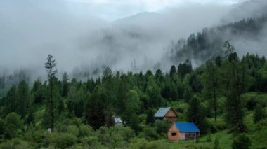 Bulutların zamanı Altai dağlarında, Kazakistan 'daki evlerin üzerinden geçiyor.