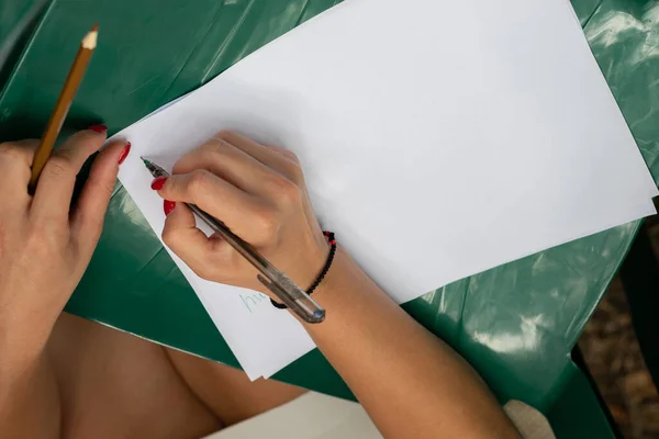 Woman\'s hand draws with pencils on white sheets