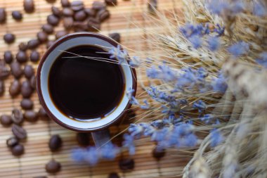Sabahleyin kahve masasında kahve çekirdekleri ve lavanta çiçekleri karışımı, rahatlama ve canlanma kavramı.