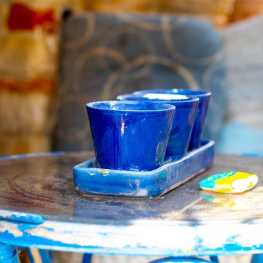 three blue ceramic mugs and a colored stone