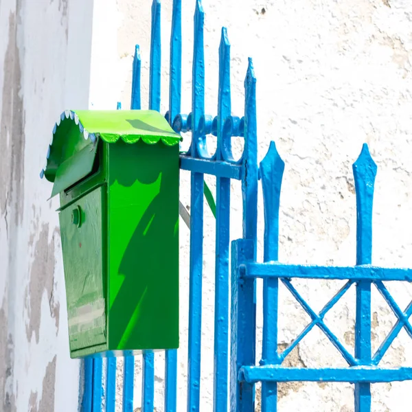 green mailbox on a blue metal fence