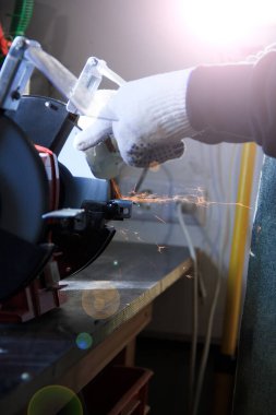 Keskinleştirme makinesi çalışıyor. Bileme makinesinde bıçağı olan bir erkek eli.. 