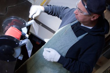 Bir adam bileme makinesinde bıçağı biler. Marangozluk aletleri.