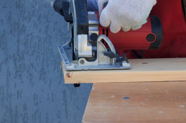 Elektrikli testereyle çalışan bir adam. Marangozluk aletleri.