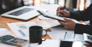 businesswoman working at office with document on her desk, doing planning analyzing the financial report, business plan investment, finance analysis concept. Using calculator and tablet.