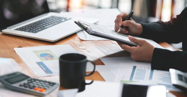 businesswoman working at office with document on her desk, doing planning analyzing the financial report, business plan investment, finance analysis concept. Using calculator and tablet.