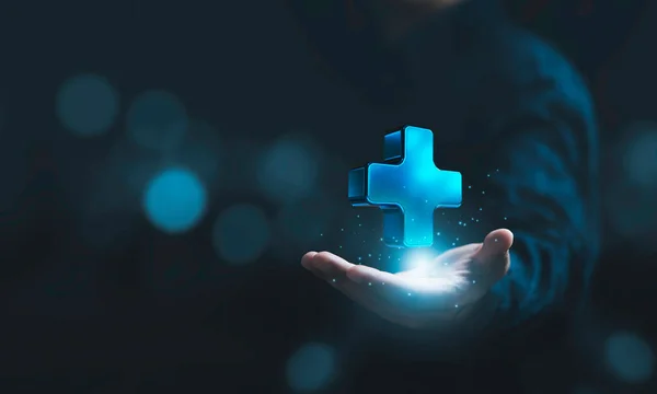 İş adamının elinde pozitif düşünme anlayışı ya da sağlık sigortası sembolü kavramı için sanal mavi artı işareti var.