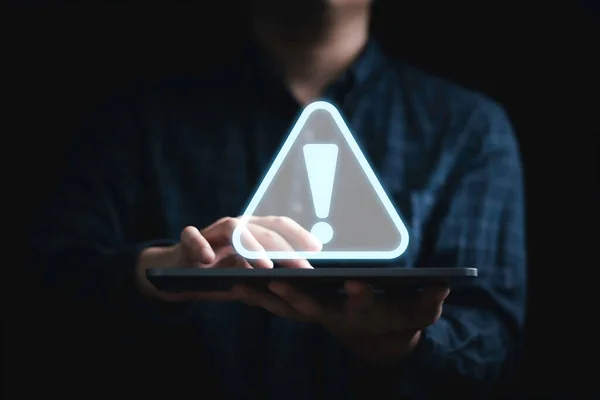Businessman holding tablet with triangle caution warning sing for notification error and maintenance concept.