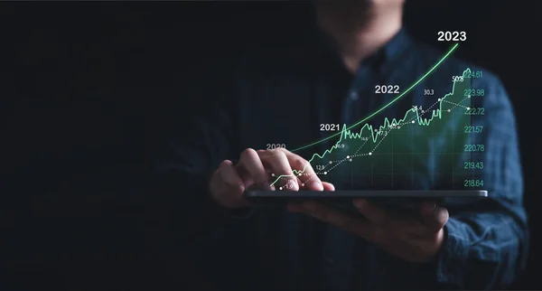 Investor holding tablet with increasing stock market graph chart for trader technical analysis concept.